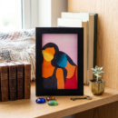 Framed abstract watercolour of two figures merged as sun and starry night, in orange, blue and pink
